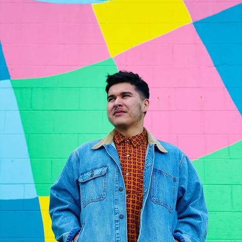 Billy-Ray Belcourt in front of a colourful background